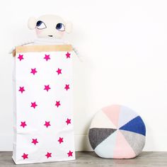 a stuffed animal sitting next to a bag with red stars on it and a ball