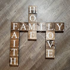 a cross made out of wooden blocks with the words family love spelled in it on a wood floor