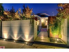 an entrance to a house with lights on the sides and plants growing in the front yard