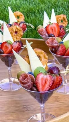 some fruit is sitting in small glasses on a wooden table with other food items and garnishes