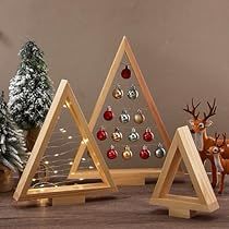 three wooden christmas trees with ornaments in them on a wood table next to other decorations