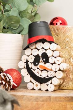 a snowman made out of logs sitting on top of a table next to christmas decorations