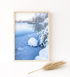 an image of a frozen river with snow on the ground and some grass in front of it