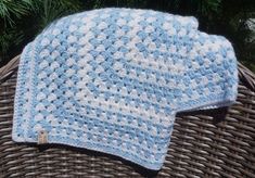 two blue and white crocheted hats sitting on top of a wicker basket