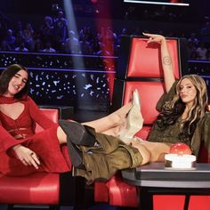 two women sitting on red chairs in front of a table