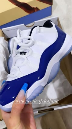 a person holding a blue and white sneaker in their hand with the box open