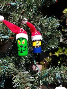 two christmas ornaments hanging from a tree with green and red hats on it's heads