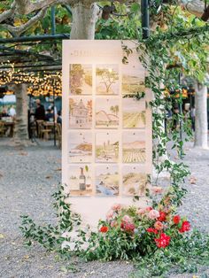 an outdoor seating area with flowers and greenery on the ground next to a tree