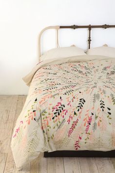 a bed with a white and pink comforter on it's side next to a wooden floor