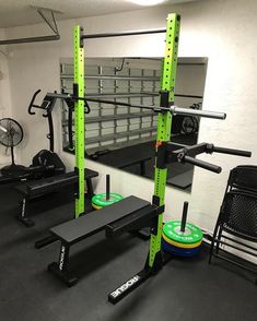 an empty gym room with squat racks, benches and exercise equipment on the floor in front of a mirror