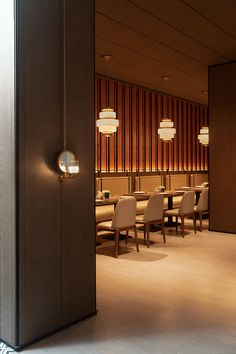 an open door leading to a dining room with white chairs and wood paneled walls