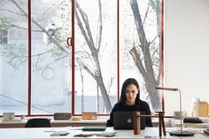 a woman sitting at a desk in front of a laptop computer