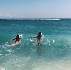 two women are in the ocean on their surfboards