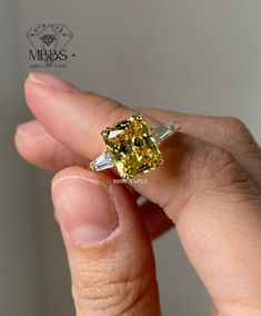 a woman's hand holding a fancy yellow diamond