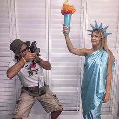 a man and woman dressed up as the statue of liberty, one holding an item in her hand