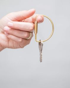 a hand holding a key ring with a small metal object attached to it's end