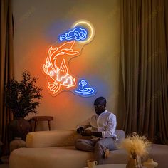 a man sitting on top of a couch in front of a neon sign that reads fish