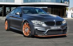 a grey car with orange rims parked in front of a building