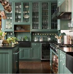 a kitchen with green cabinets and wooden floors, pots and pans hanging from the ceiling