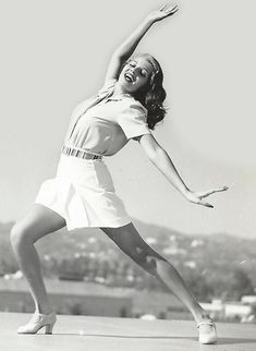 a black and white photo of a woman in mid - air with her arms outstretched