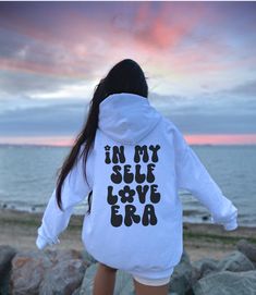 Hey, you fabulous soul! Get ready to groove in your very own Self Love Era with this super fun and empowering hoodie! We've decked it out with a funky retro font that proudly shouts "In My Self Love Era" on the back. And that's not all! The front rocks a cool "Self Love Club" design to spread good vibes all around! This hoodie isn't just stylish, it's also crazy comfy, making it your go-to outfit for daily adventures and self-loving escapades. Wrap yourself in its soft and cozy embrace, and let Hoodie Saying Ideas, I Love You Say It Back Sweatshirt, Saying Sweatshirts, I Love You Say It Back, Hoodies With Sayings, Quote Hoodies, Stile Hijab, Hoodie Quotes, Sweatshirt Aesthetic