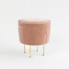 a pink velvet stool with gold legs on a white background in front of a plain backdrop