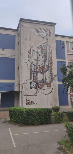 a building with a mural painted on the side of it's wall in front of a parking lot