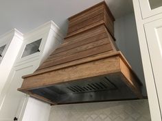 a wooden stove hood in a kitchen with white cabinets