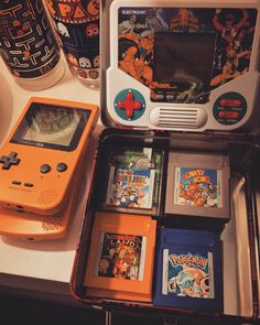 an orange gameboy sitting on top of a table next to other games and accessories