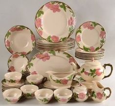 a collection of porcelain dishes, cups and saucers with pink flowers on the rims