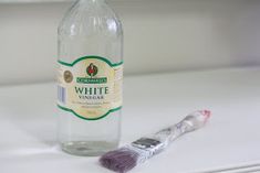 a toothbrush sitting next to a bottle of white wine on a counter with a window in the background