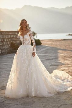 a woman in a wedding dress standing on a stone walkway with her hands on her hips