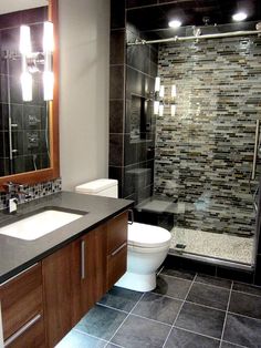 a bathroom with a toilet, sink and shower stall in the middle of it's tile flooring