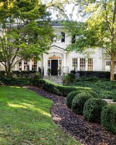 a large white house surrounded by trees and bushes