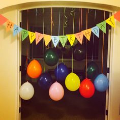 balloons and streamers are hanging from the ceiling in front of a birthday party entrance