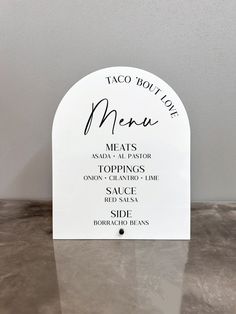 a sign that says taco boution menu next to a table with silverware on it