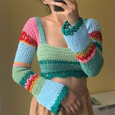 a woman is wearing a colorful crochet sweater while talking on her cell phone