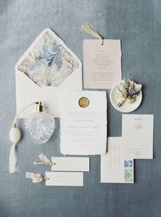 the wedding stationery is laid out on a blue tablecloth with white and gold accents