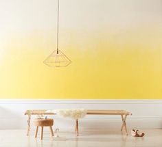 a room with yellow walls and two benches in front of the bench is a light fixture that hangs from the ceiling