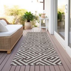 an outdoor area rug on a deck with furniture and potted plants in the background