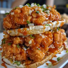 two fried chicken sandwiches stacked on top of each other with sauce and green onions in the middle