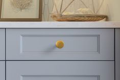 a close up of a drawer with two pictures on the wall behind it and a basket in the background