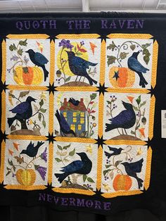 a quilted wall hanging with black birds and pumpkins on it's sides