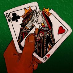 a hand holding two playing cards in front of a green background with the queen and king of spades