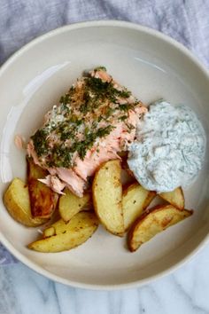 a white bowl filled with food on top of a marble countertop next to potato wedges