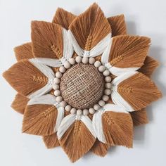 a brown and white flower with wooden beads on it's center, hanging from the wall