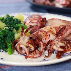 an octopus is sitting on a plate next to broccoli and other food items