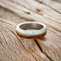 a wooden ring sitting on top of a piece of wood with green and white stripes