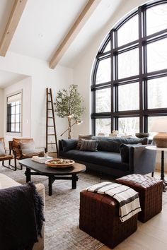 a living room filled with lots of furniture next to a large window covered in windows