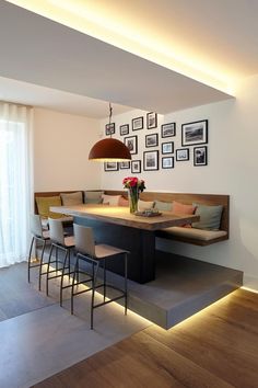 a dining room table with chairs and pictures on the wall above it, along with bar stools